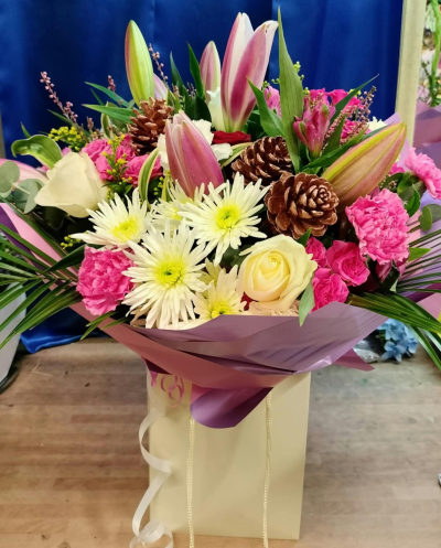 Blush Lily Hand-tied - Seasonal pink lily and rose gift bag with chrysanthemums, carnations and pinecones. Handcrafted by Four Seasons Florist for birthdays and special occasions.